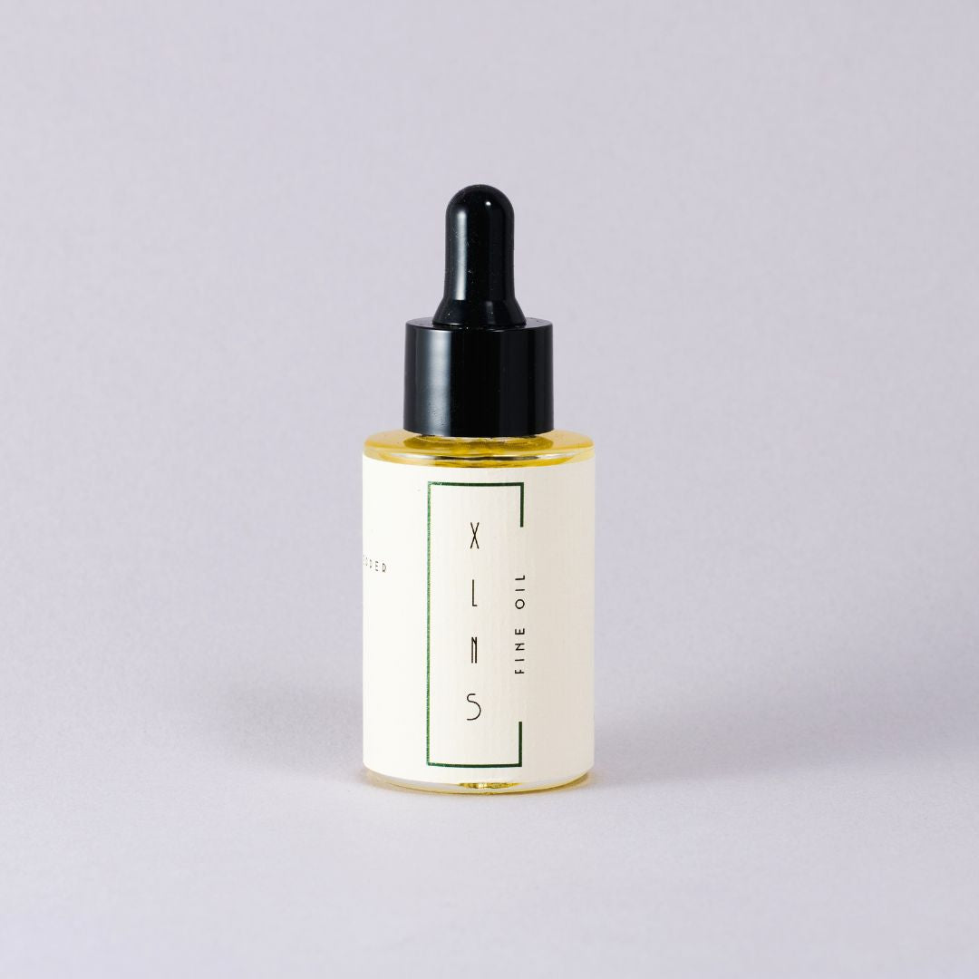 Bottle of XLNS skincare oil with dropper on a light gray background