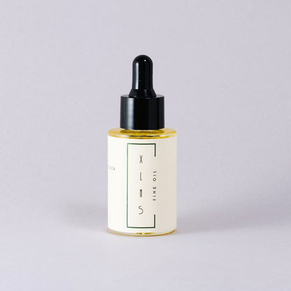 Bottle of XLNS skincare oil with dropper on a light gray background